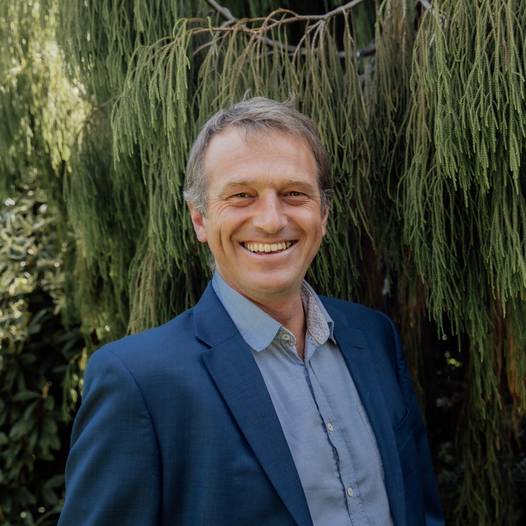 Robin Mitchell wearing a suit, smiling at camera